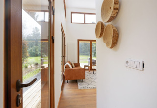Entree van tiny house Woody Lodge Valerie bij Holiday Resort 't Schuttenbelt met zicht op woonkamer en tuin.