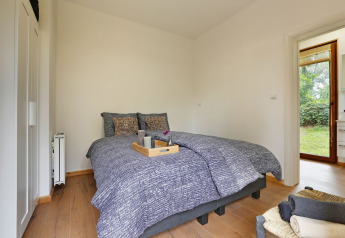 Slaapkamer Woody Lodge Valerie in Holiday Resort 't Schuttenbelt, met dubbel bed en zicht op de tuin.