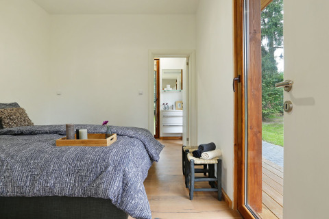 Slaapkamer in Woody Lodge Valerie op Holiday Resort 't Schuttenbelt met zicht op badkamer en tuin.