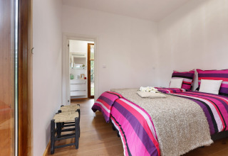 Dormitorio en Woody Lodge Valerie, Holiday Resort 't Schuttenbelt, con ropa de cama colorida y decoración moderna.