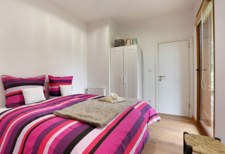Slaapkamer in Woody Lodge Valerie, Holiday Resort 't Schuttenbelt, Nederland, met gestreept beddengoed.
