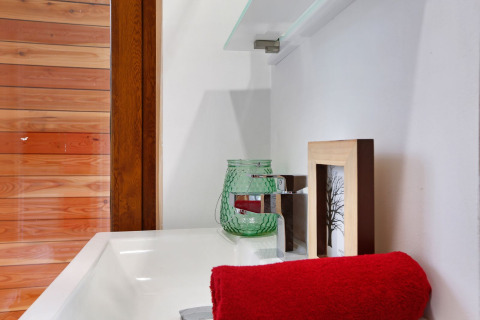 Close-up van een wasbak met rood handdoek en glazen decoratie in Woody Lodge Valerie, Nederland.