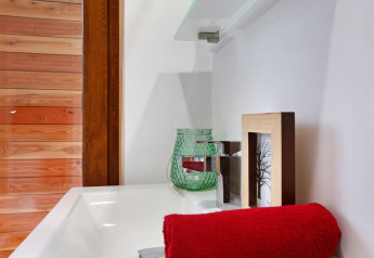 Close-up van een wasbak met rood handdoek en glazen decoratie in Woody Lodge Valerie, Nederland.