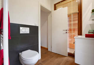 Modern badkamerinterieur in Woody Lodge Valerie met wandcloset, wastafel en toegang tot een privé sauna.