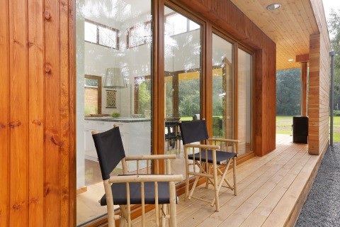 Wooden patio with two chairs outside Woody Lodge Valerie at Holiday Resort 't Schuttenbelt in the Netherlands.