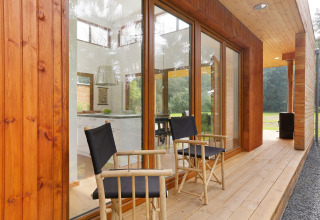 Wooden patio with two chairs outside Woody Lodge Valerie at Holiday Resort 't Schuttenbelt in the Netherlands.