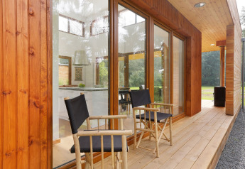 Terraza de madera con dos sillas frente a Woody Lodge Valerie en Holiday Resort 't Schuttenbelt, Países Bajos.