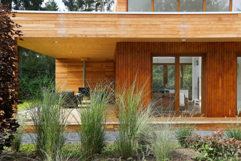 Casa piccola in legno Woody Lodge Valerie, terrazza e aiuole verdi nel resort 't Schuttenbelt nei Paesi Bassi.
