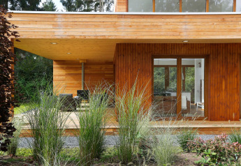 Moderne tiny house Woody Lodge Valerie met houten gevel, terras en siergrassen in Twente, Nederland.