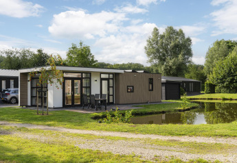 Moderne lodge aan vijver bij Holiday Park De Lochemse Berg in Nederland met terras en uitzicht op de natuur.