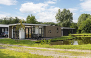 Moderne lodge aan vijver bij Holiday Park De Lochemse Berg in Nederland met terras en uitzicht op de natuur.