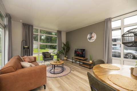 Woonkamer in The Water Lily lodge bij Holiday Park De Lochemse Berg, met modern interieur en grote ramen.