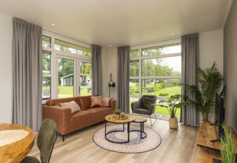 Living room of The Water Lily lodge at Holiday Park De Lochemse Berg in the Netherlands with modern decor and large windows.