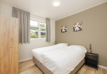 Slaapkamer in The Water Lily lodge op Holiday Park De Lochemse Berg, Nederland, met twee bedden en stijlvolle inrichting.