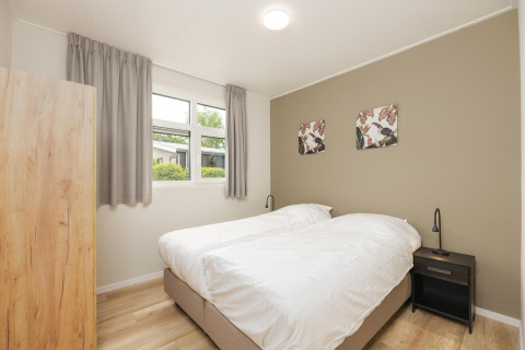 Slaapkamer in The Water Lily lodge op Holiday Park De Lochemse Berg, Nederland, met twee bedden en stijlvolle inrichting.