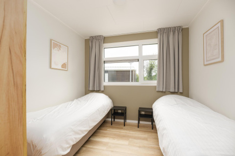Bright bedroom with two single beds and large window at The Water Lily lodge, Holiday Park De Lochemse Berg, Netherlands.