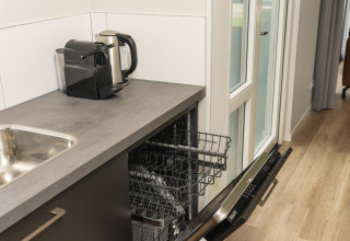 Kleine kitchenette met vaatwasser, koffiezetapparaat en waterkoker in The Water Lily, Holiday Park De Lochemse Berg.