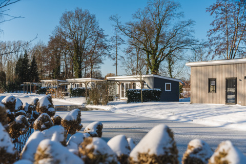 Sneeuwbedekte huisjes bij Lodge Mistique, Holiday Park De Lochemse Berg, Nederland, op een winterse dag.