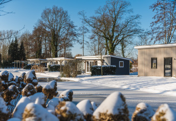 Sneeuwbedekte huisjes bij Lodge Mistique, Holiday Park De Lochemse Berg, Nederland, op een winterse dag.