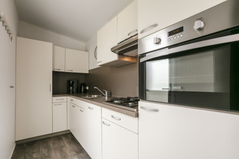 Moderne keuken in Lodge Mistique op Holiday Park De Lochemse Berg, Nederland, met witte kasten en oven.