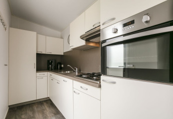Moderne keuken in Lodge Mistique op Holiday Park De Lochemse Berg, Nederland, met witte kasten en oven.