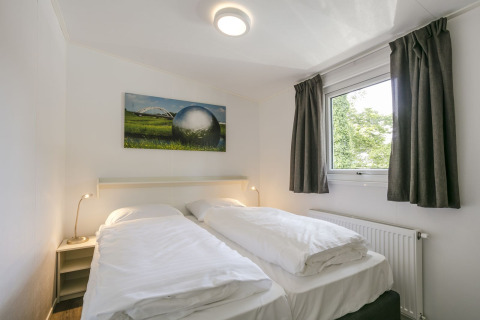 Slaapkamer in Lodge Mistique bij Holiday Park De Lochemse Berg met twee eenpersoonsbedden en raam.