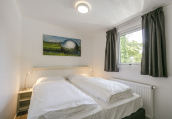 Slaapkamer in Lodge Mistique bij Holiday Park De Lochemse Berg met twee eenpersoonsbedden en raam.