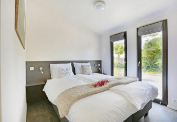 Modern slaapkamer met tweepersoonsbed en grote ramen in Lodge Grand Modern, Holiday Park De Lochemse Berg.