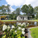 Lodge moderno con stagno, fiori bianchi e area relax al Holiday Park De Lochemse Berg, Paesi Bassi.