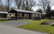 Moderne hytte ved Holiday Park De Lochemse Berg i Holland, med terrasse, havemøbler og grøn have.