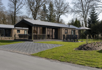 Lodge moderne au Holiday Park De Lochemse Berg aux Pays-Bas, avec terrasse, chaises et jardin vert.