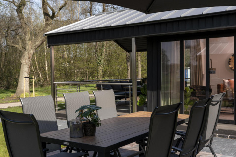 Mesa de comedor al aire libre y sillas en la terraza de una cabaña en Holiday Park De Lochemse Berg, Países Bajos.