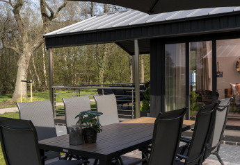 Udendørs spisebord og stole på en terrasse ved en lodge i Holiday Park De Lochemse Berg, Holland.