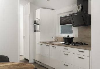 Cucina moderna della Terrace Lodge a De Lochemse Berg con mobili bianchi, piano cottura a gas e cappa nera.