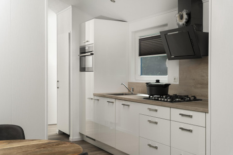 Moderne keuken in de Terrace Lodge, De Lochemse Berg, met witte kasten, gaskookplaat en zwarte dampkap.