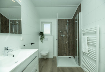 Moderne badkamer in Terrace Lodge, Holiday Park De Lochemse Berg, Nederland, met glazen douchecabine.