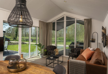 Woonkamer in Terrace Lodge, Holiday Park De Lochemse Berg, Nederland, met modern interieur en grote ramen.