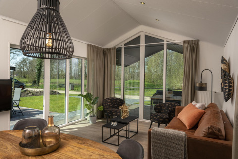 Wohnzimmer der Terrace Lodge im Holiday Park De Lochemse Berg, Niederlande, mit modernen Möbeln und großen Fenstern.