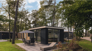 Moderna Kubus Lodge con sauna al Holiday Park De Lochemse Berg nei Paesi Bassi, immersa tra gli alberi.