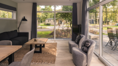 Lyst interiør i Kubus Lodge med store vinduer, udsigt til natur, og moderne indretning i Holland.