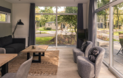 Licht interieur van Kubus Lodge met grote ramen, modern meubilair en uitzicht op De Lochemse Berg.