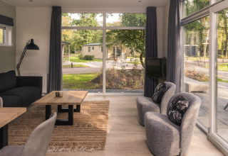 Licht interieur van Kubus Lodge met grote ramen en zicht op de natuur in Holiday Park De Lochemse Berg.