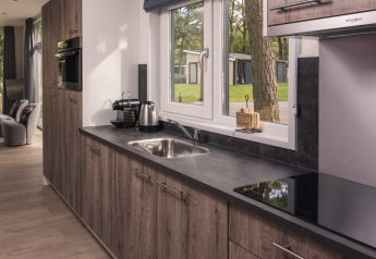 Moderne keuken van Kubus Lodge + sauna in Holiday Park De Lochemse Berg, met uitzicht op de groene natuur.