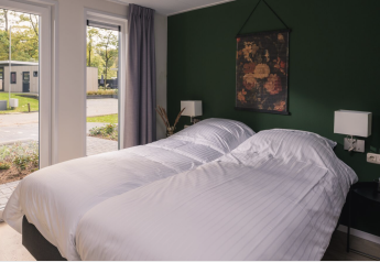 Modernes Schlafzimmer mit zwei Einzelbetten, weißen Bettbezügen und Blick nach draußen in der Kubus Lodge, Niederlande.