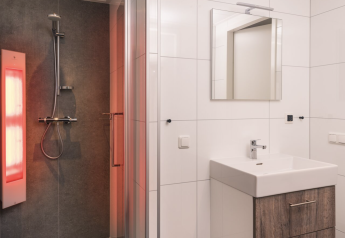 Moderne badkamer in Kubus Lodge + sauna, Holiday Park De Lochemse Berg, met douche en grote wastafel.