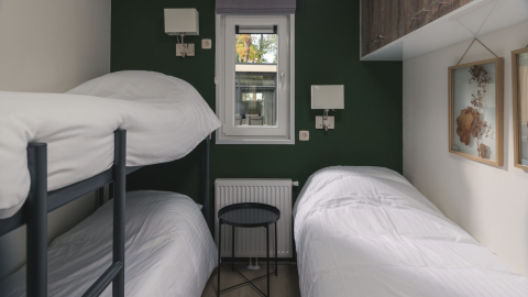Kleine slaapkamer met stapelbed en eenpersoonsbed in de Kubus Lodge + sauna, Holiday Park De Lochemse Berg, Nederland.