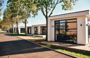 Modern lodges at Villa Maritiem in MarinaPark Bad Nederrijn, Netherlands, featuring trees and glass walls.