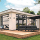 Moderne Lodge Villa Maritiem im MarinaPark Bad Nederrijn mit Holzterrasse, Sofaecke und Sonnenschirm.