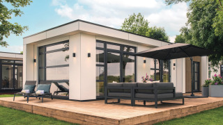 Lodge moderno Villa Maritiem al MarinaPark Bad Nederrijn con terrazza in legno, divano e grande ombrellone.