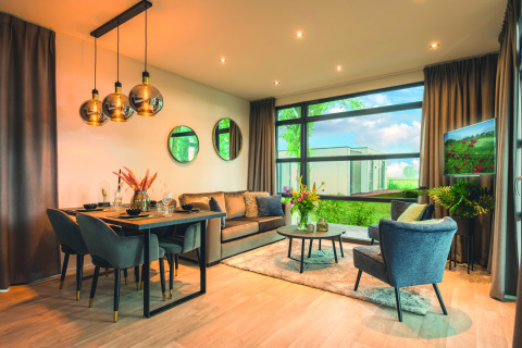 Moderne woonkamer in Villa Maritiem lodge met eettafel, knusse zithoek en grote ramen met uitzicht.